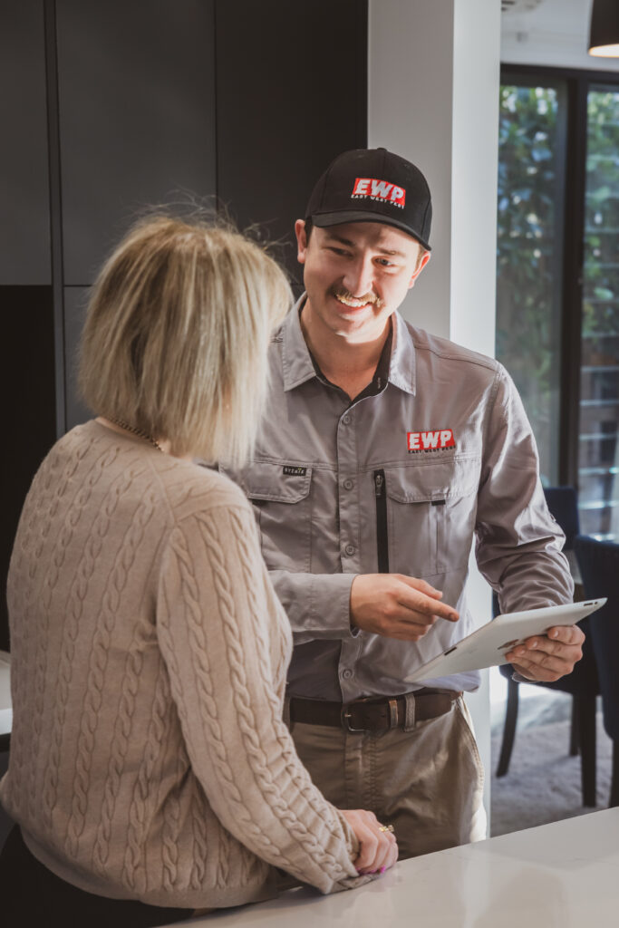 Ben from East West Pest talking with a customer while holding a tablet